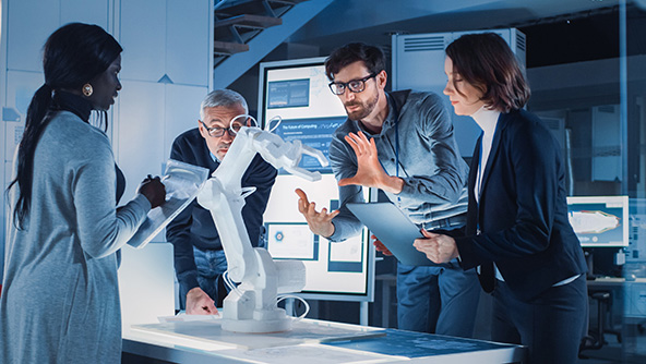 Four people talking together around a measuring machine