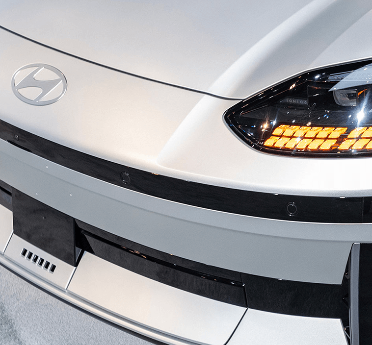 Close-up of Hyundai Ioniq 6 front grille and headlight, featuring sleek curves and illuminated amber accents