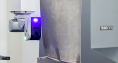 A 3D laser scanner attached to a coordinate measuring machine. The scanner is positioned so the blue laser is visible