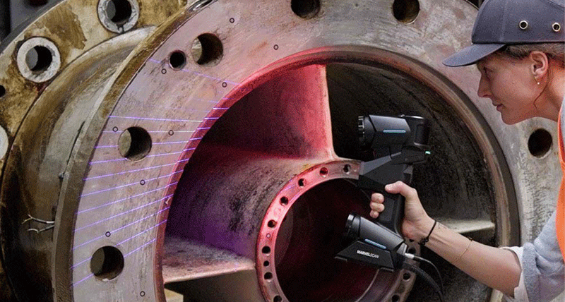 An engineer inspecting a metal object with a handheld 3D scanner
