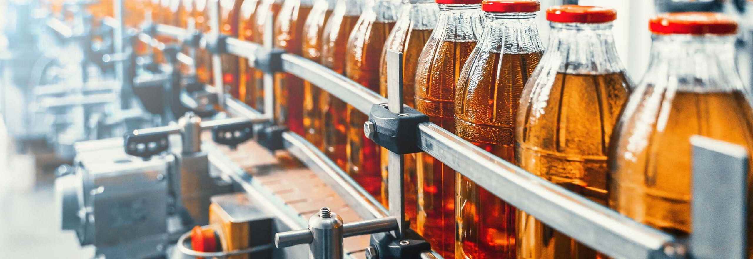Image of a conveyor belt of drinks bottles filled with an orange drink