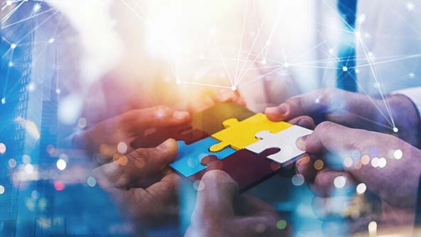 Business professionals combining puzzle pieces, symbolizing strategic partnership and collaborative teamwork.
