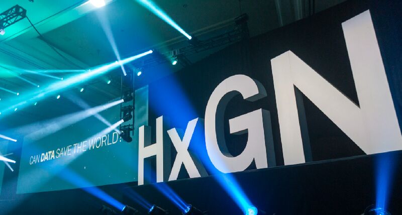 Un palcoscenico con scritte H x G N e luci sullo sfondo. 