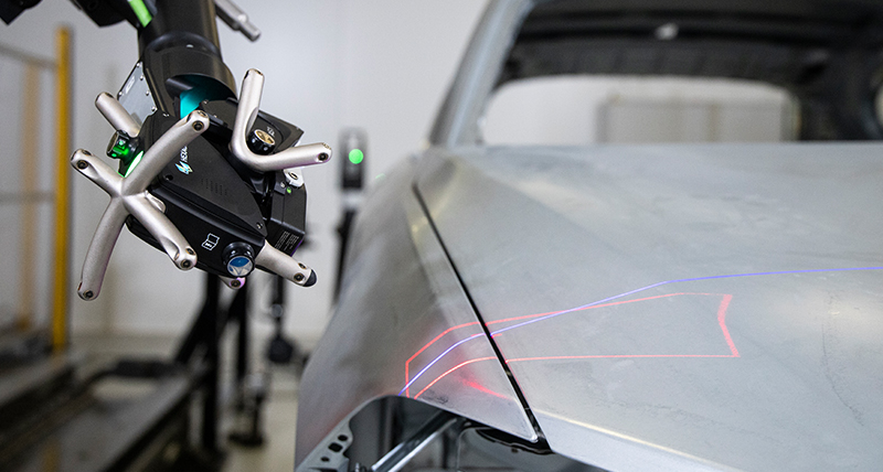 Image of robotic arm with lasers on car body 