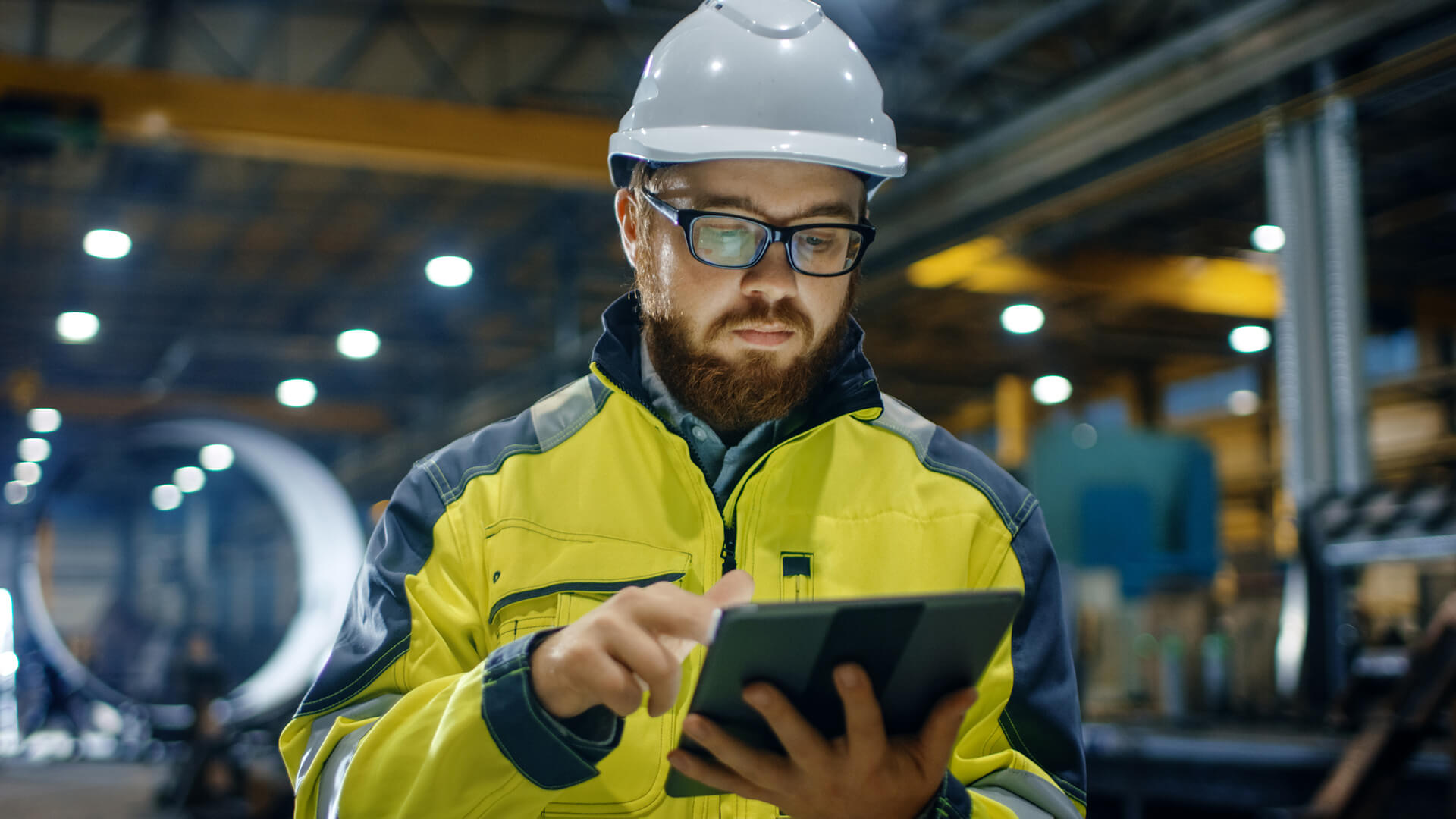 Industrial Engineer in Hard Hat Wearing Safety Jacket Uses Touchscreen Tablet Computer