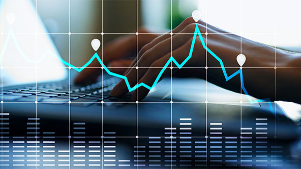 Persons hands at a laptop with a graph and grid blue overlay to imply working with statistics