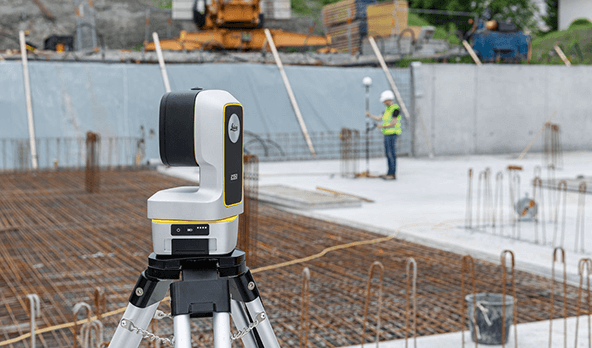 Leica iCON sensor on a tripod at a construction site, with a worker using another sensor on a rebar-filled foundation.