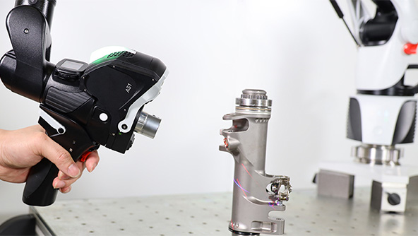 A 3d laser scanner inspecting a metal pipe object on a workbench the base of the portable measuring arm the scanner is mounted can be seen in the background