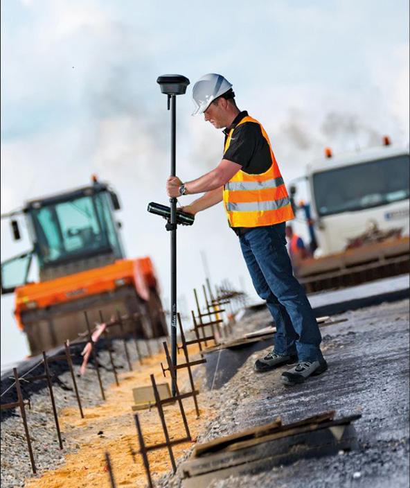 surveyor measures a point on a road construction site using a smart antenna