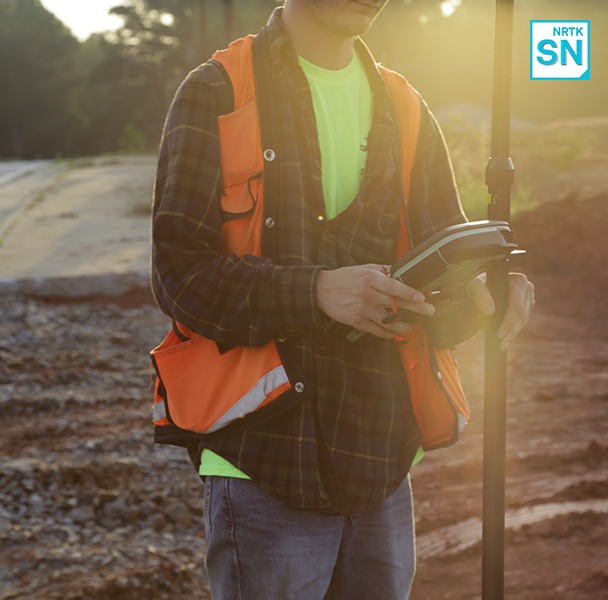 A surveyor measures on a construction site using GNSS and network RTK correction serivces