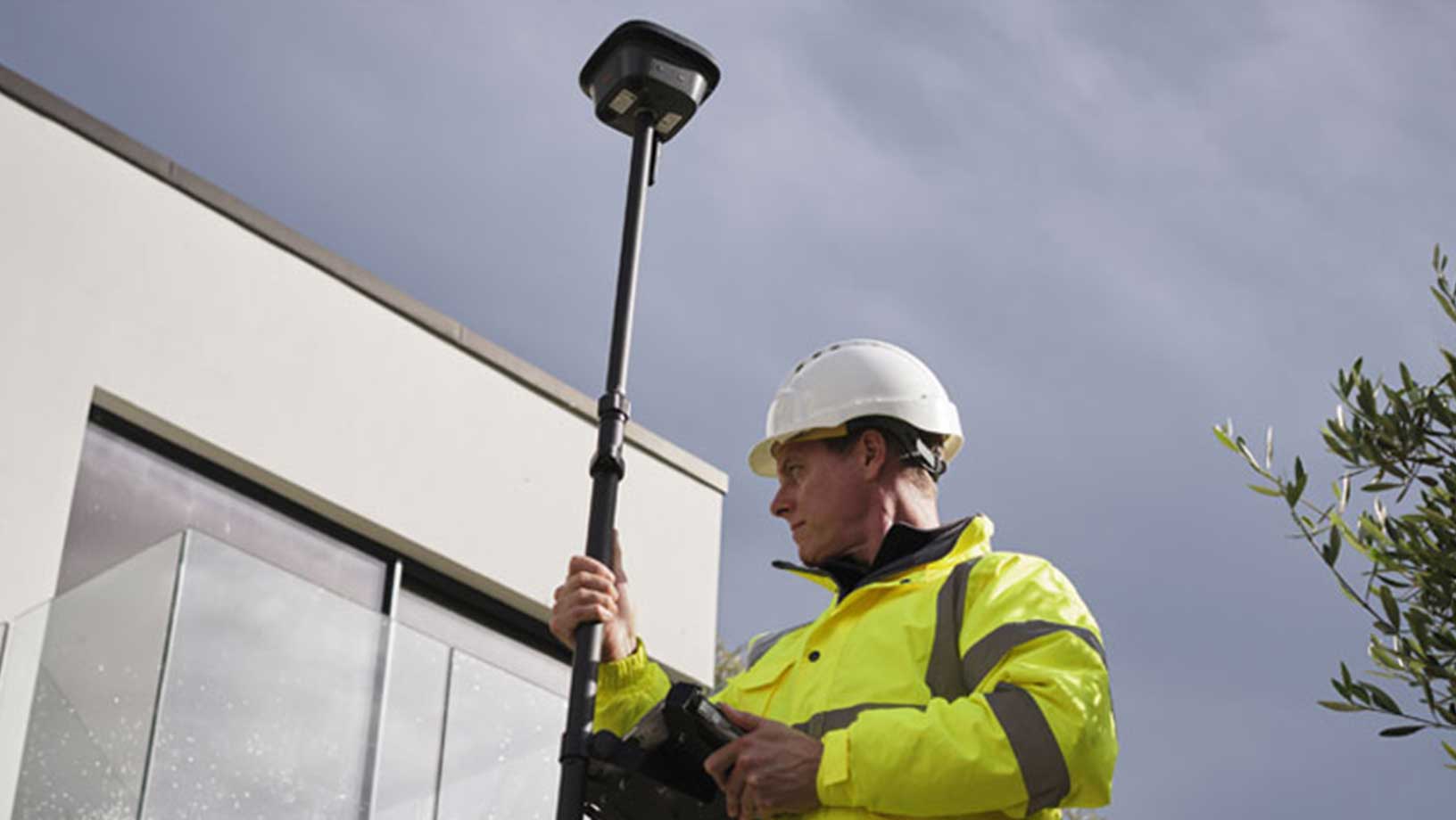 Trabalhador do sexo masculino usando o RTK GNSS móvel Leica da Hexagon