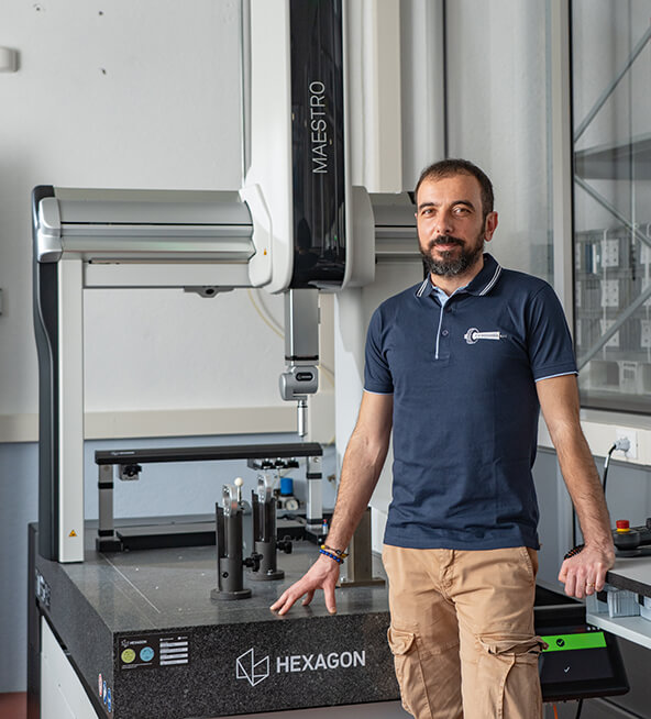 Raffaele Caforio beside a HEXAGON MAESTRO coordinate measuring machine in a bright metrology lab with precision fixtures