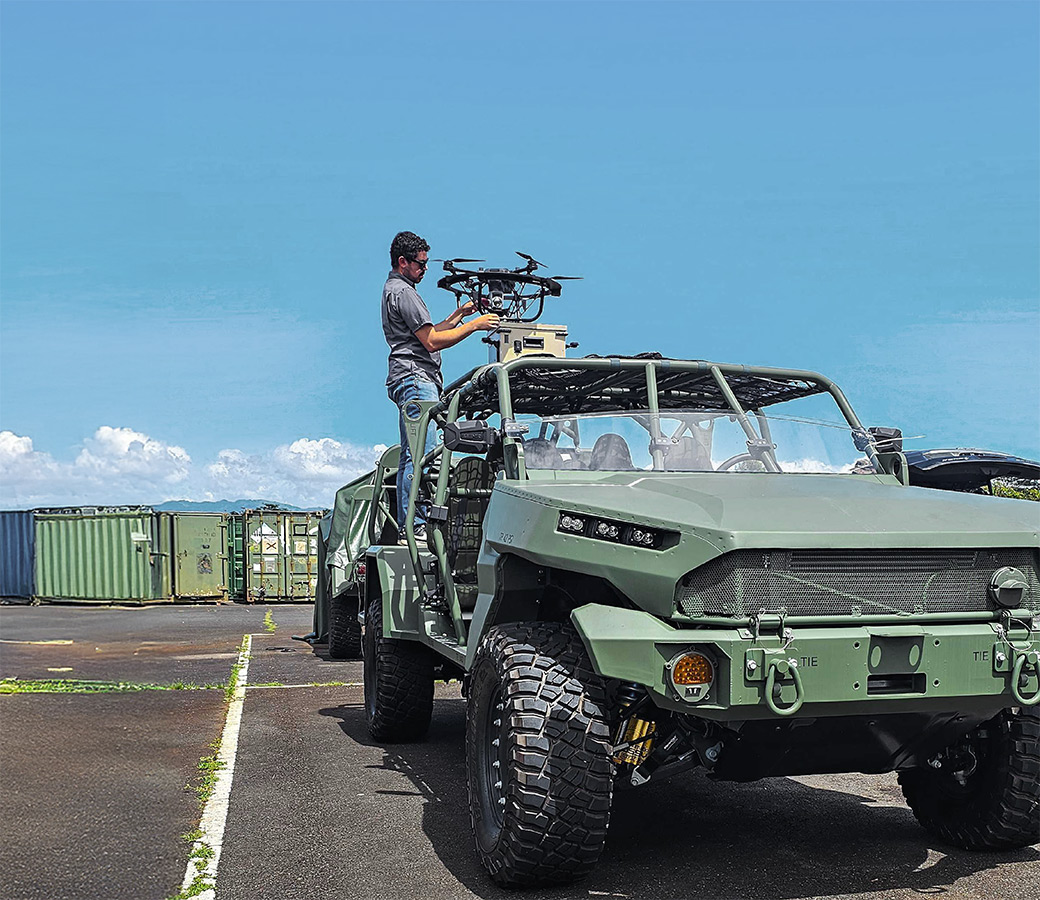 A man preparing a drone on top of a vehicle
