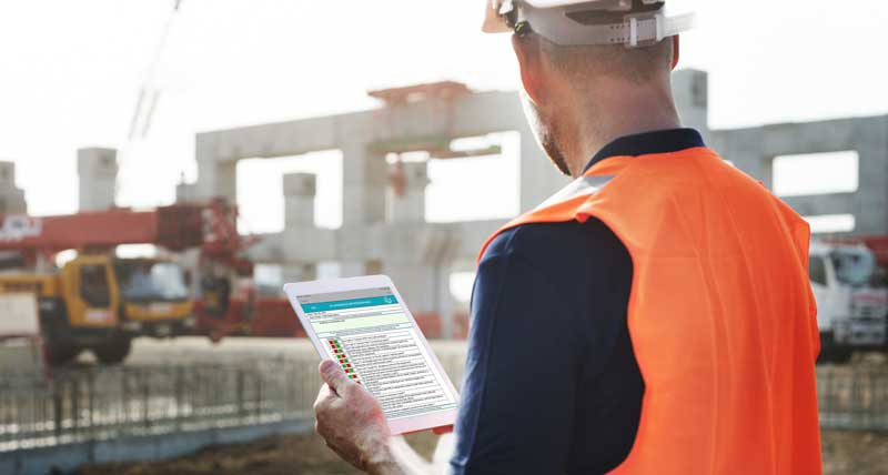 Construction worker using the job hazard analysis solution on his tablet to evaluate and report hazards on the job site. 