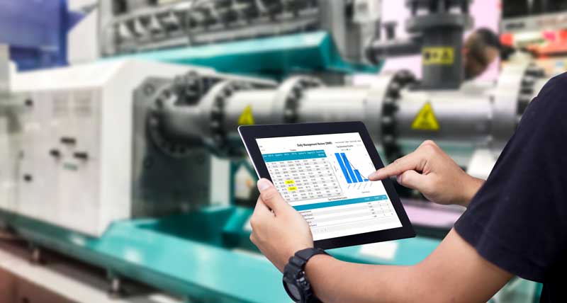 Manufacturing worker in industrial facility using the OEE dashboard app on his tablet to review OEE and KPI data to report back to the office. 