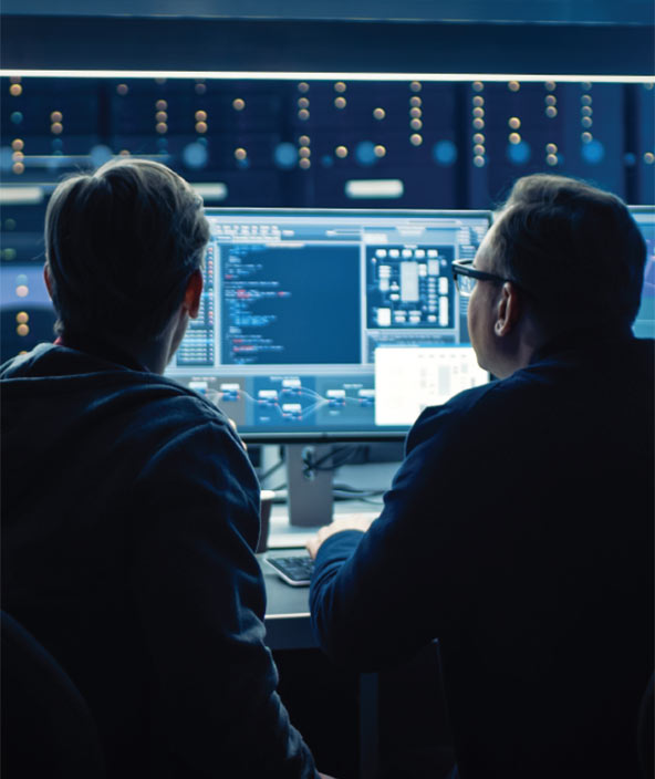 two people looking working on a computer in a dark room