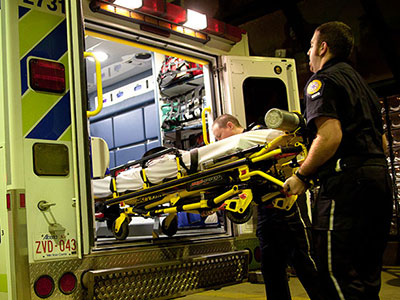 Emergency personnel loading a stretcher into ambulance