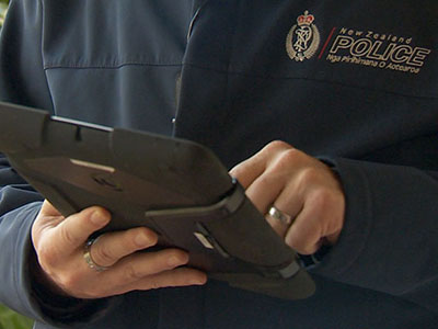 Oficial de policía de Nueva Zelanda consultando datos en una tableta