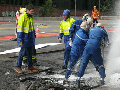Workers repair a pipeline under a section of pavement
