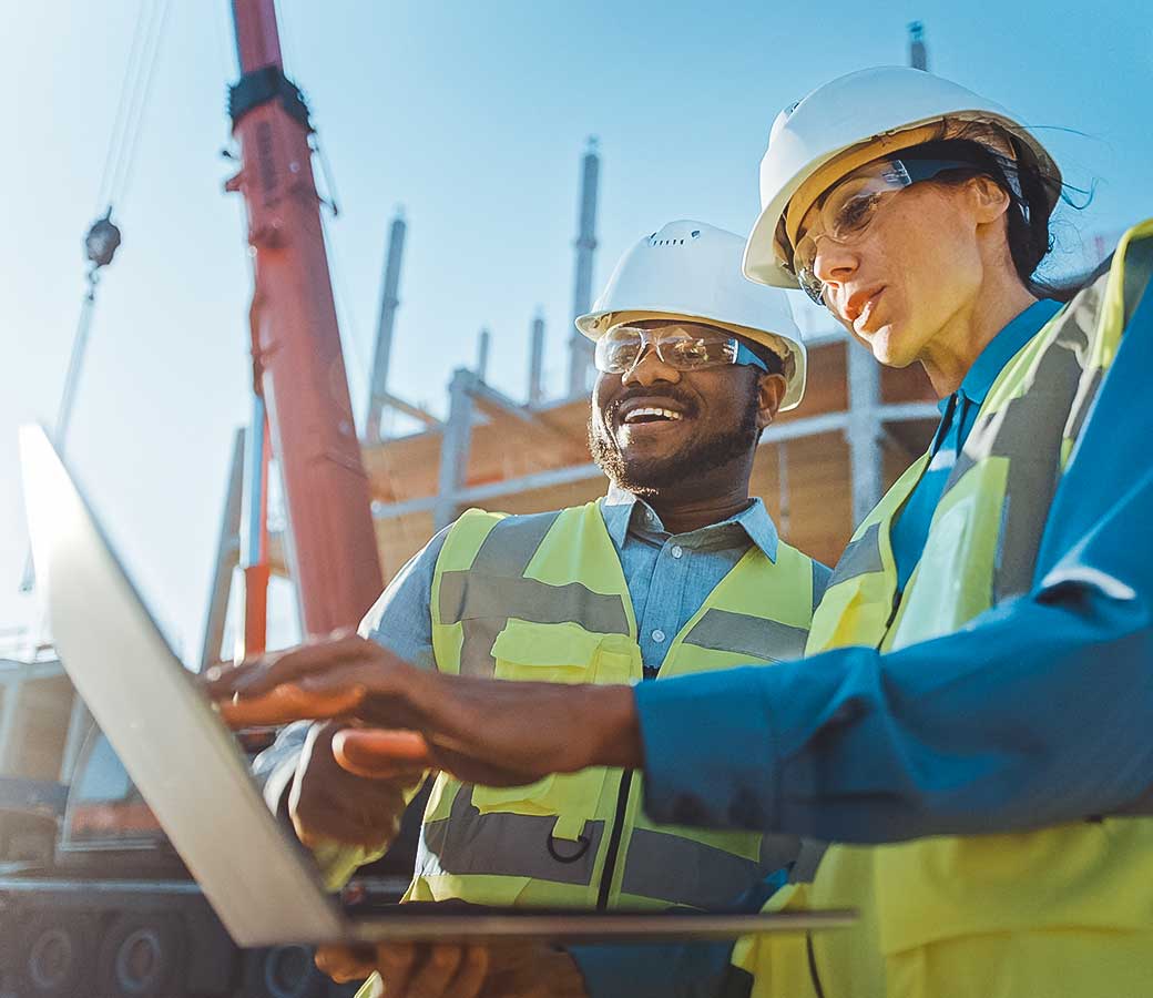 Un hombre y una mujer revisan una tablet en una obra de construcción