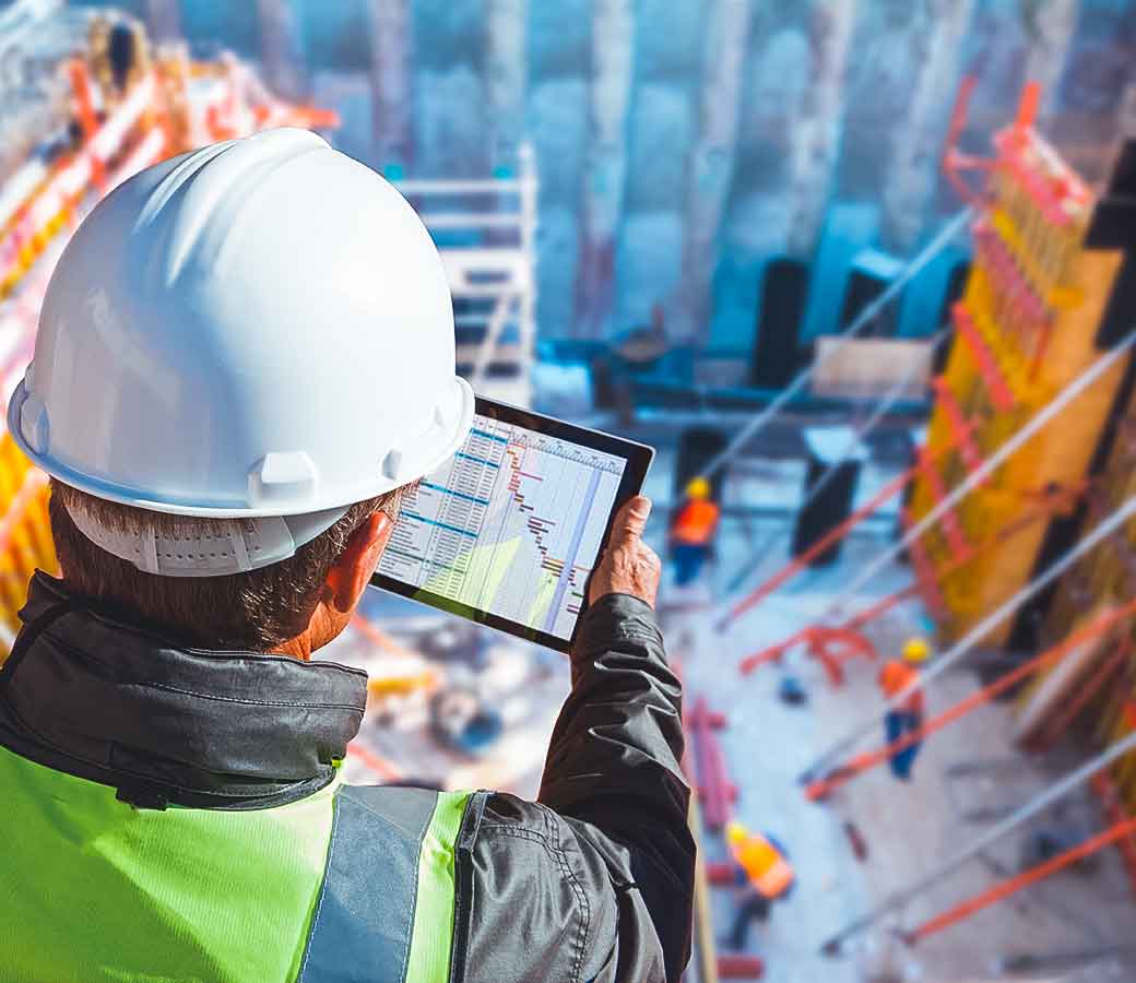 Mann schaut über eine Baustelle auf ein Tablet