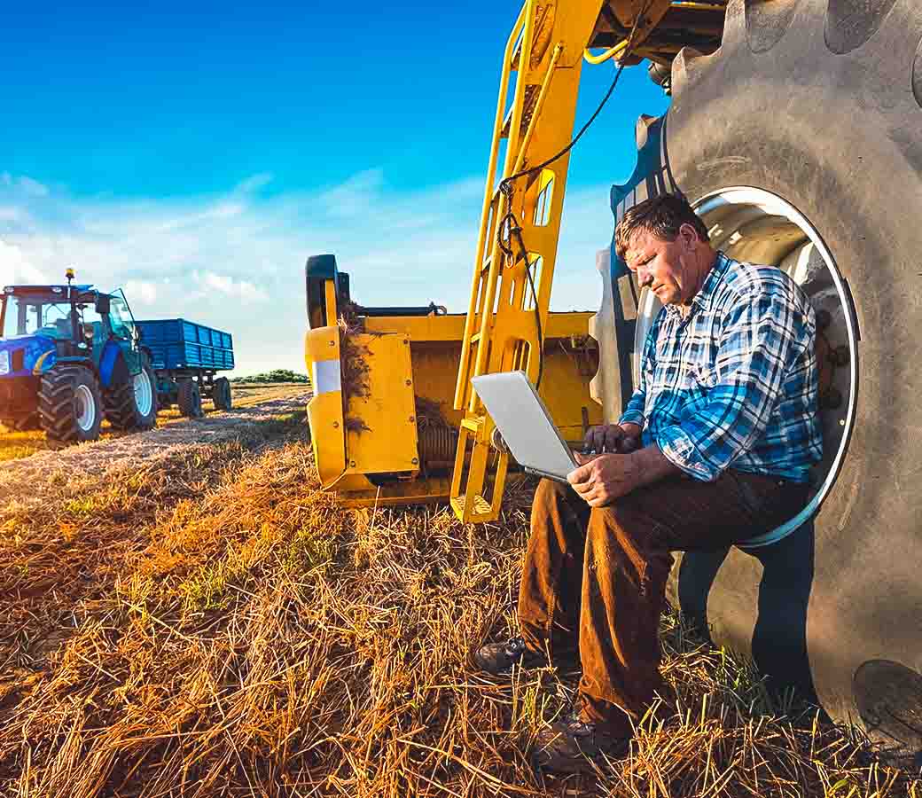 Man looking at computer while sitting in a tractor wheel