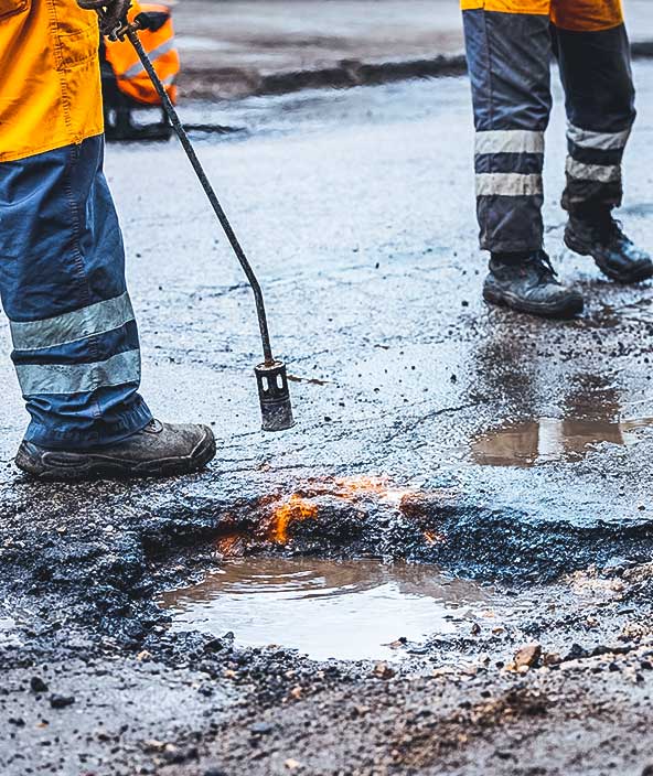 reparación de baches: trabajadores del servicio de mantenimiento trabajando en la carretera