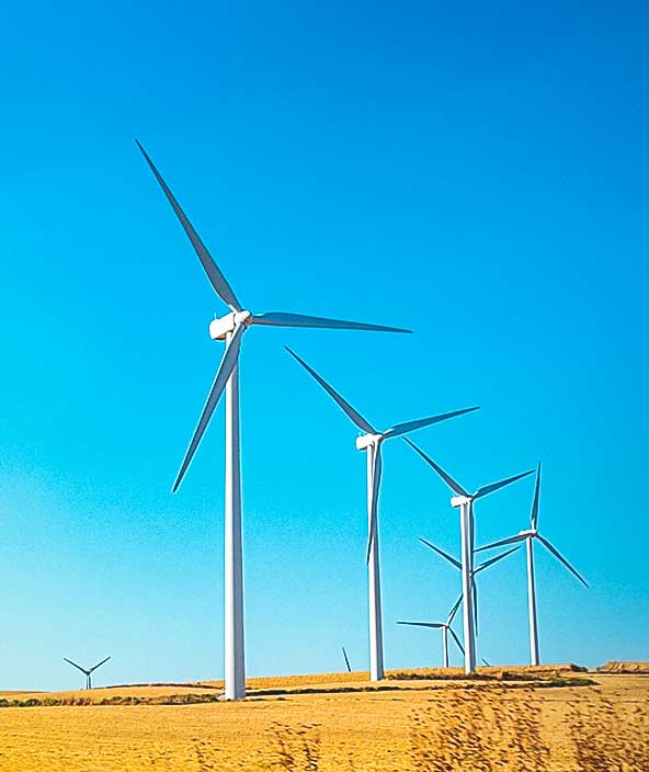 青空を背にした風景と対照的な、風力タービン発電ウインドファームの発電機