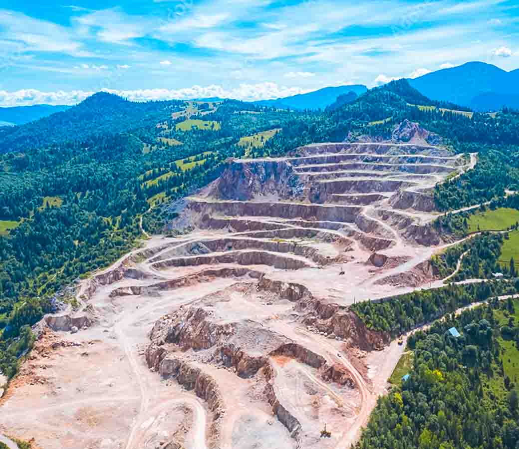 imagem aérea de uma pedreira de mineração em uma montanha verdejante