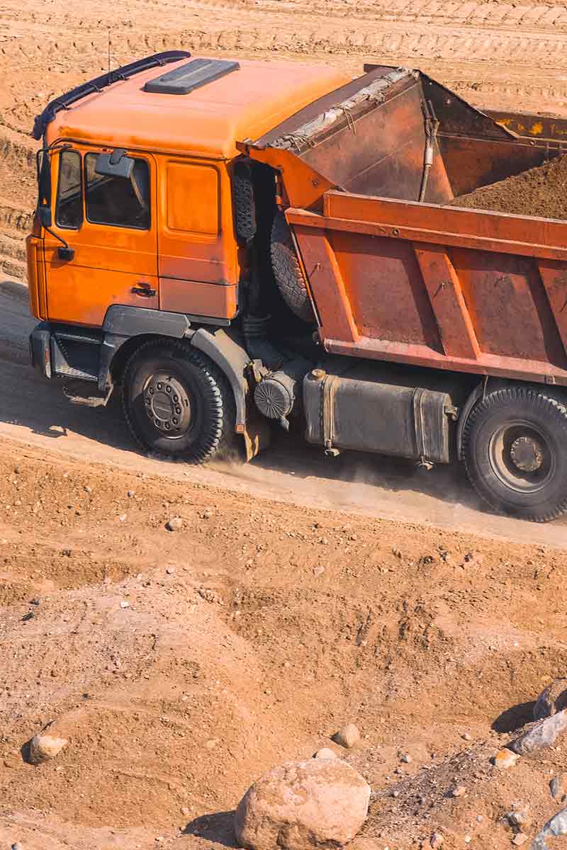 Um caminhão grande transportando materiais ao longo de um caminho de sujeira