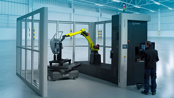 Hexagon's automated inspection cell with a robotic arm inspecting a body in white car door. An operator can be seen next to the cell programming the machine.