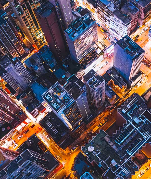 Luftaufnahme einer Großstadt mit weitläufigen Gebäuden und starkem Verkehr bei Nacht