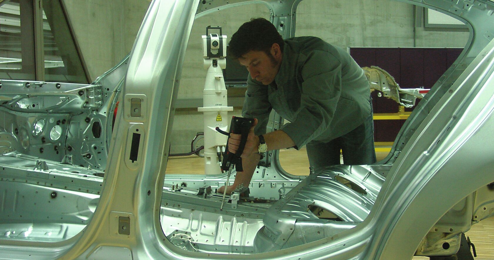 Manufacturing worker conducting a manual quality inspection of a vehicle in a manufacturing line. 
