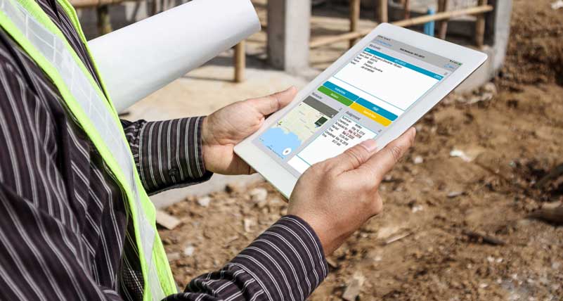 Male worker on the job site using the field service worker solution on his tablet to submit a work order. Solution is highlighted on the tablet's interface.