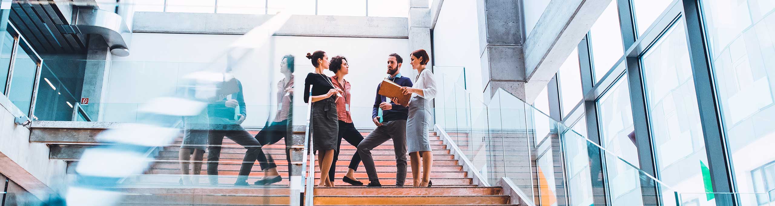 A team of colleagues stands on a staircase and converses